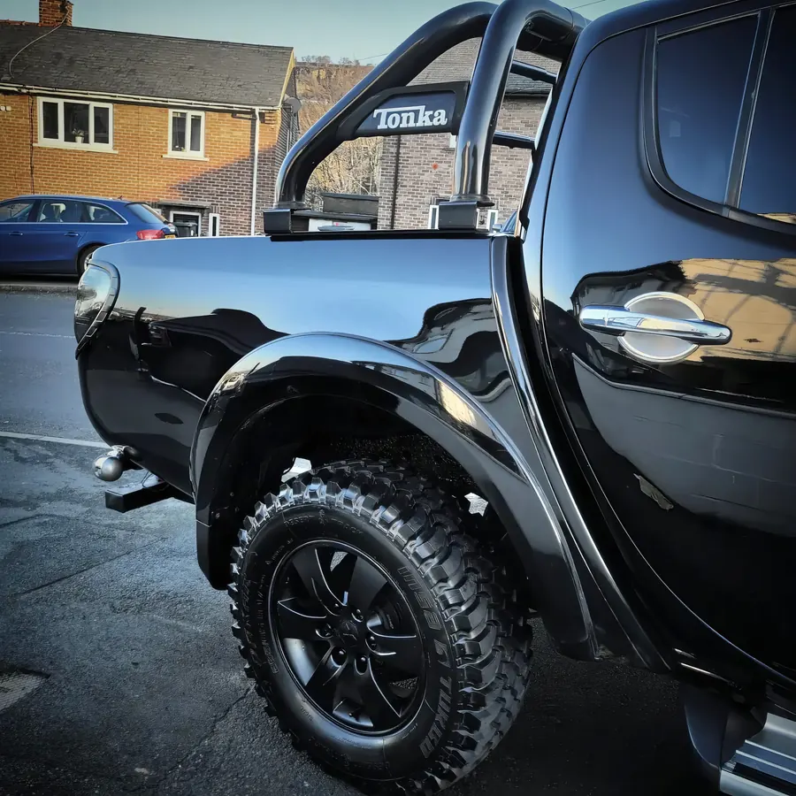 Black pickup truck with a deep gloss finish and roll bar