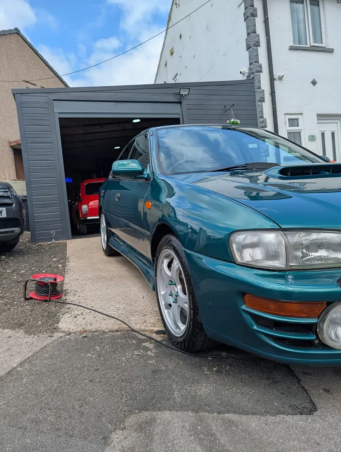 Green Subaru Impreza parked outside a garage